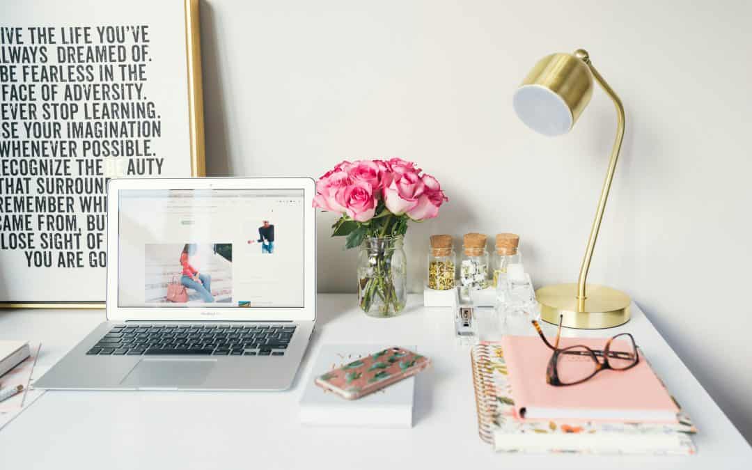 Mac Book Ait beside gold colored study lamp and spiral books.