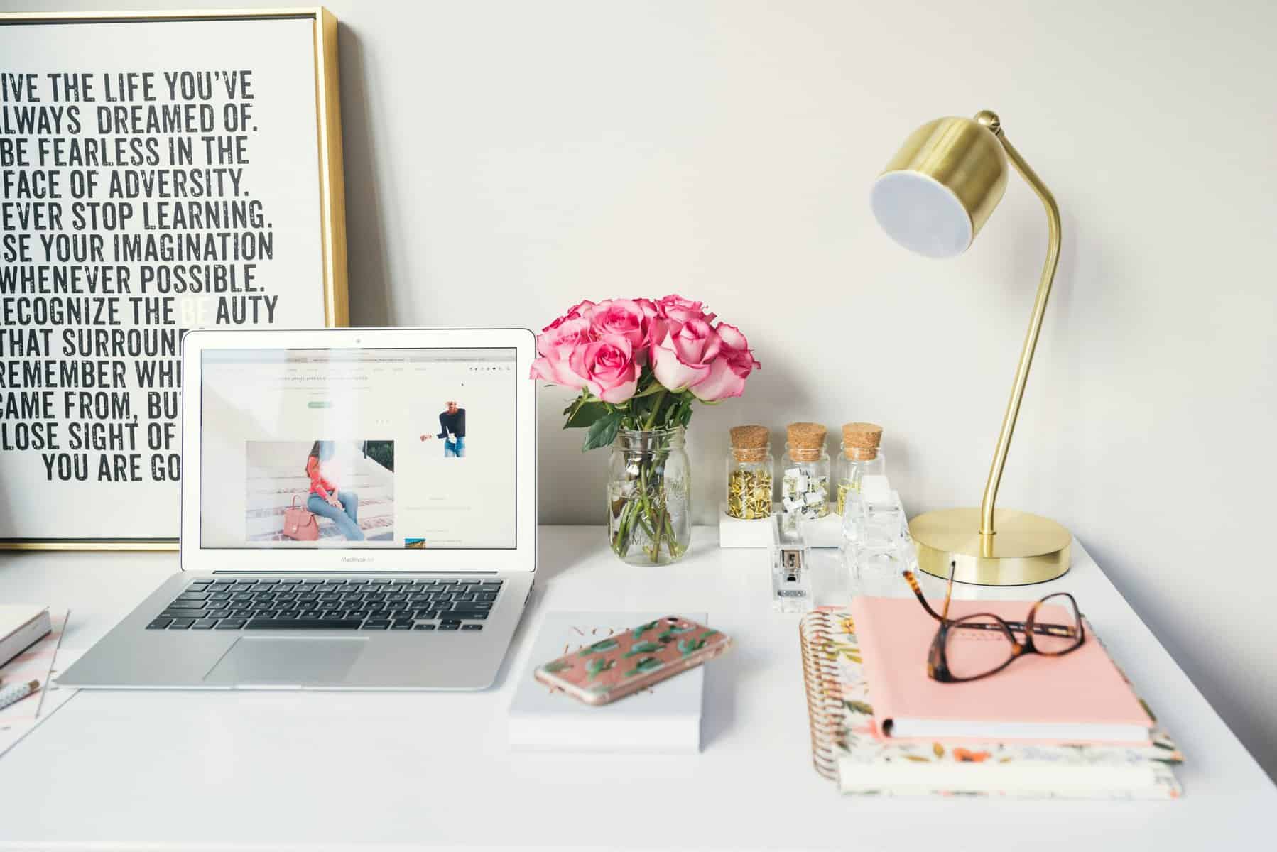 Mac Book Ait beside gold colored study lamp and spiral books.